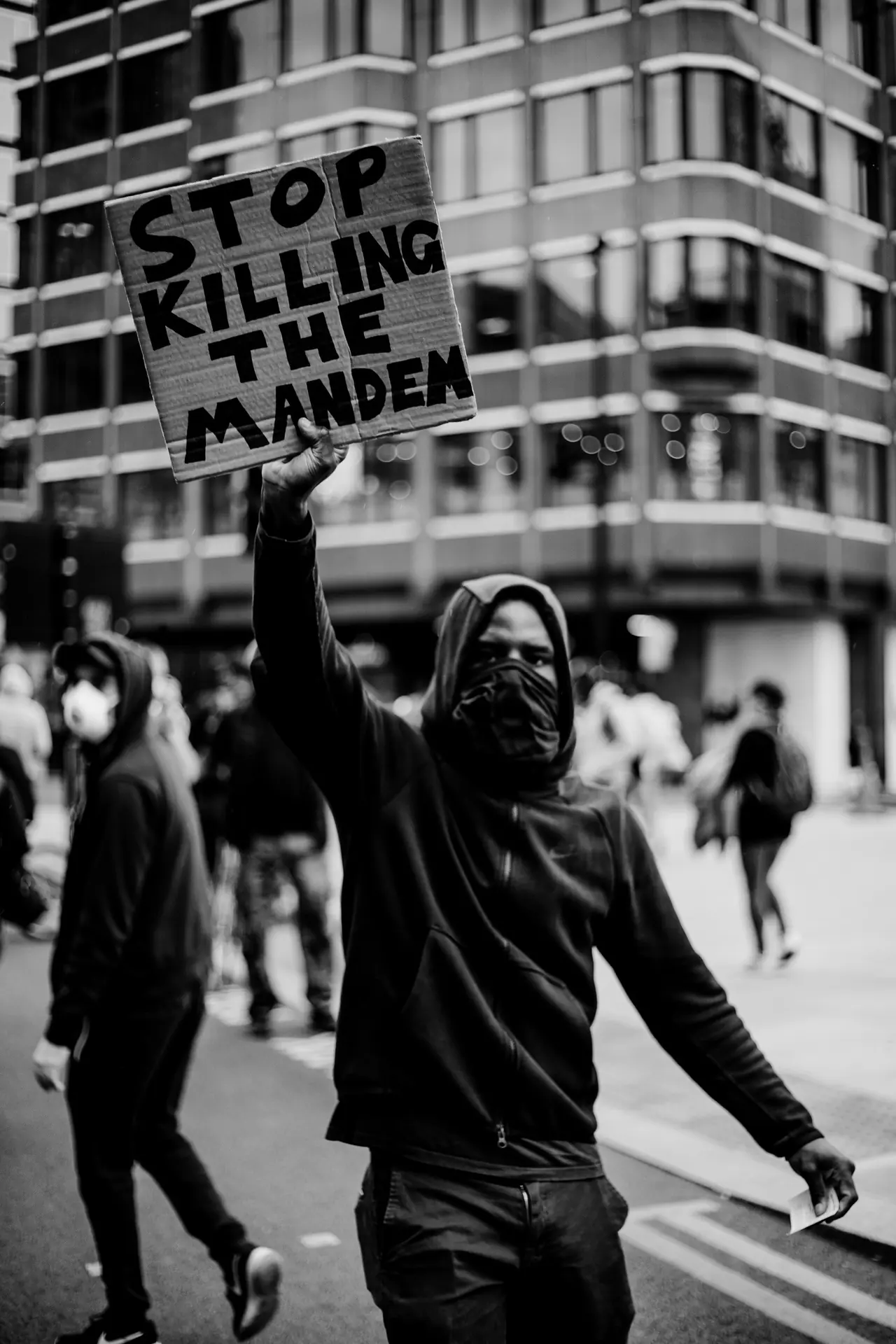 Protester holding a 'Stop killing the mandem' placard on a London street