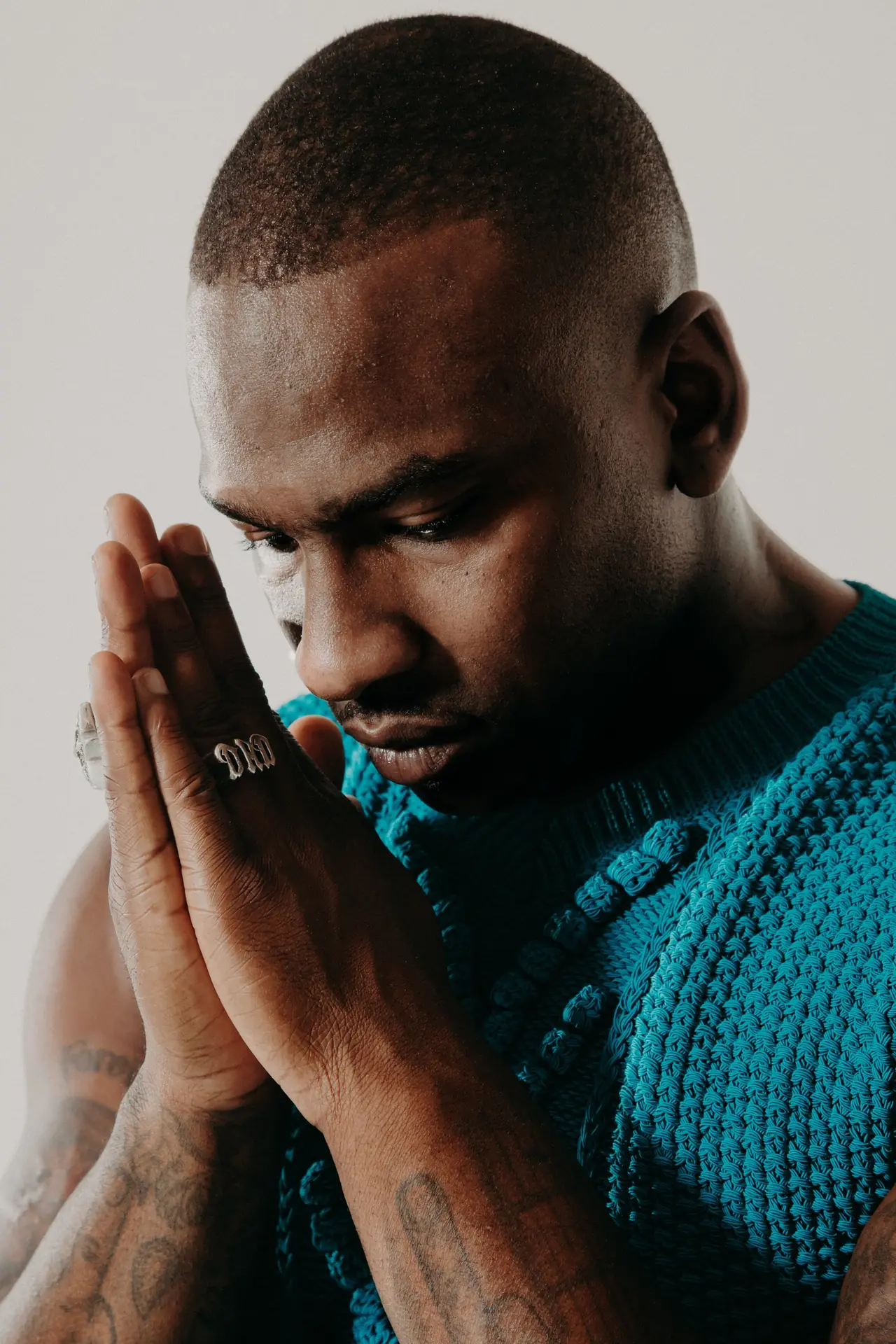 Artist in a teal knit, hands together