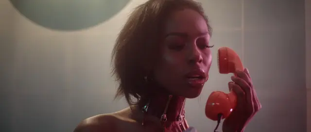 Music video still, woman on a red telephone