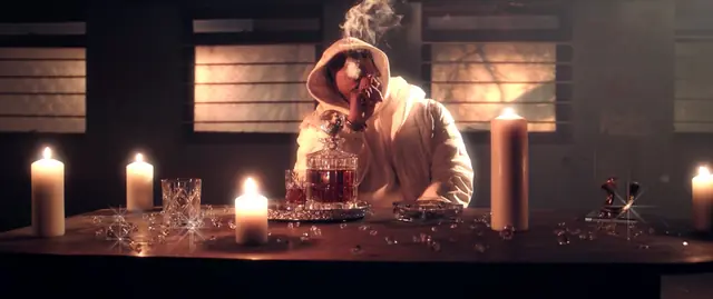 Hooded figure at a candlelit table