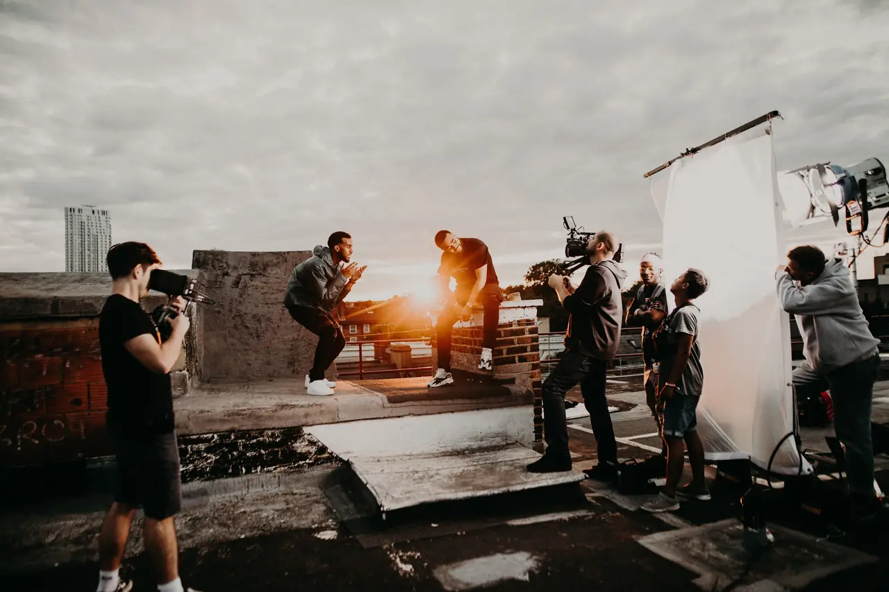Film crew shooting a performer on a rooftop at sunset