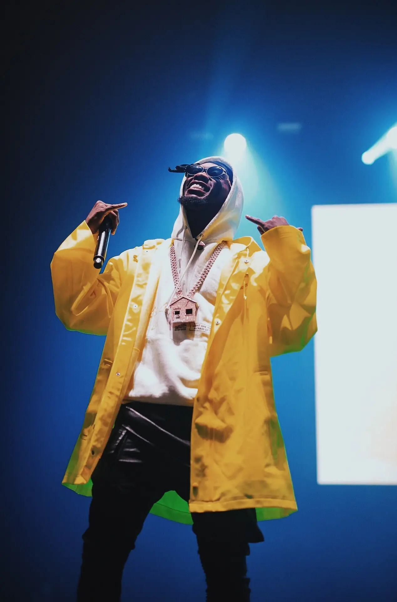 Performer in a yellow jacket on stage under blue lights